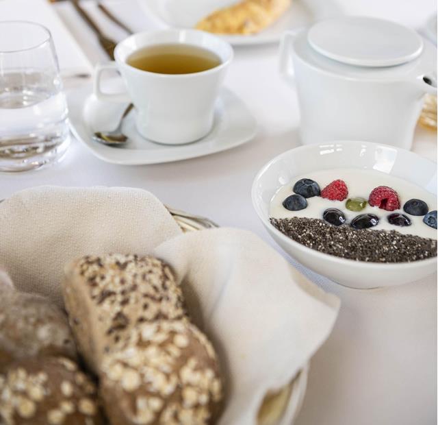 Breakfast with yogurt, chia seeds, berries, bread rolls, omelette, tea and water