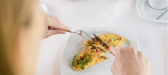 A woman is having an omelette for breakfast