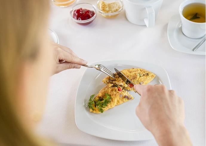 A woman is having an omelette for breakfast