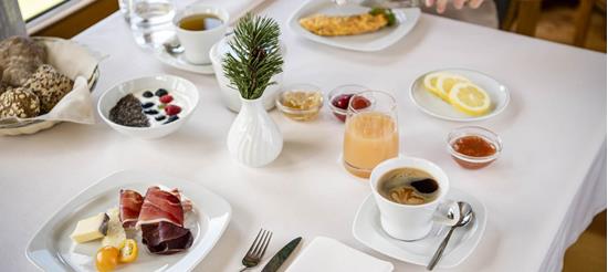 Hearty breakfast with cold cuts, cheese, omelette, yogurt, jam, coffee and juice