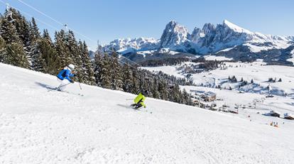 Zwei Skifahrer fahren eine schneebedeckte Piste hinunter